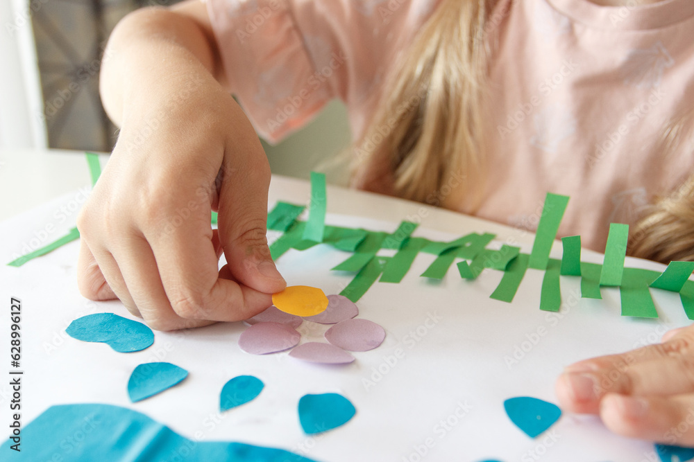 Cute child creating an applique with colored paper and glue. Concept of hobby or education Cute child creating an applique with colored paper and glue. Concept of hobby or education