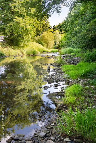 Forest spring water river with a clear reflection off the trees and rocky shore