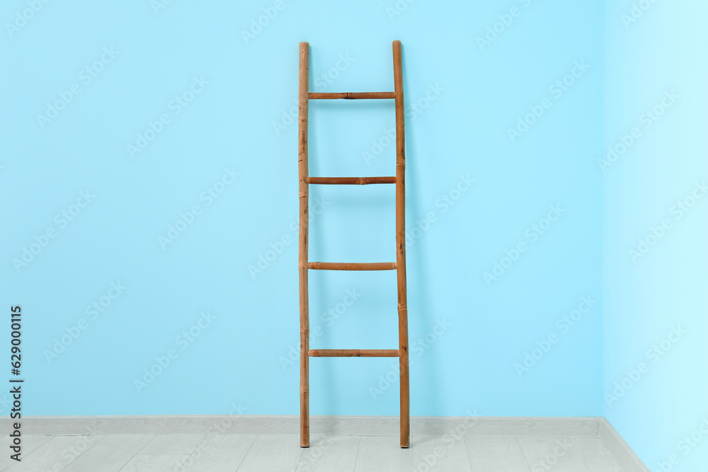 Wooden ladder near blue wall in room