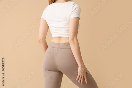 Young woman in sportswear on beige background