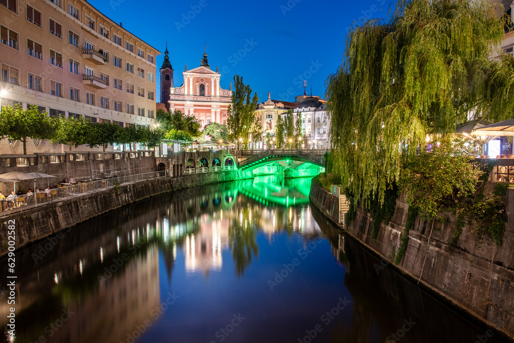 Historical city center of Ljubljana, the capital of Slovenia with an old bridge and a reflection in the Ljubljanica river at night
