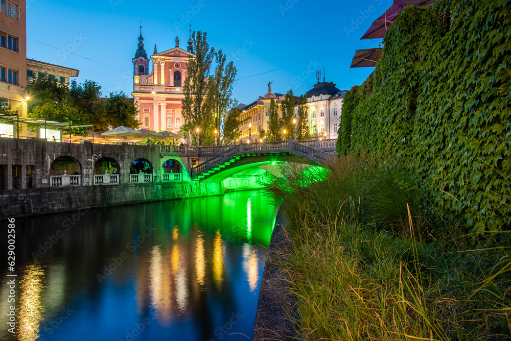 Historical city center of Ljubljana, the capital of Slovenia with an old bridge and a reflection in the Ljubljanica river at night