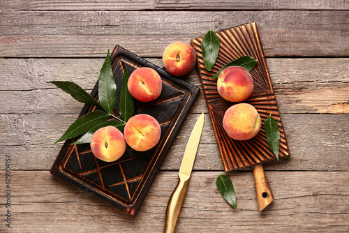 Boards with sweet peaches and leaves on wooden background