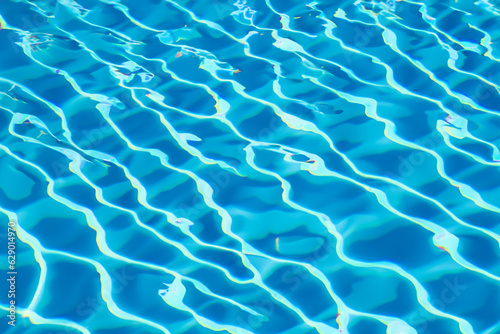 Vibrant blue water surface with captivating sunlit reflections, closeup view of a swimming pool