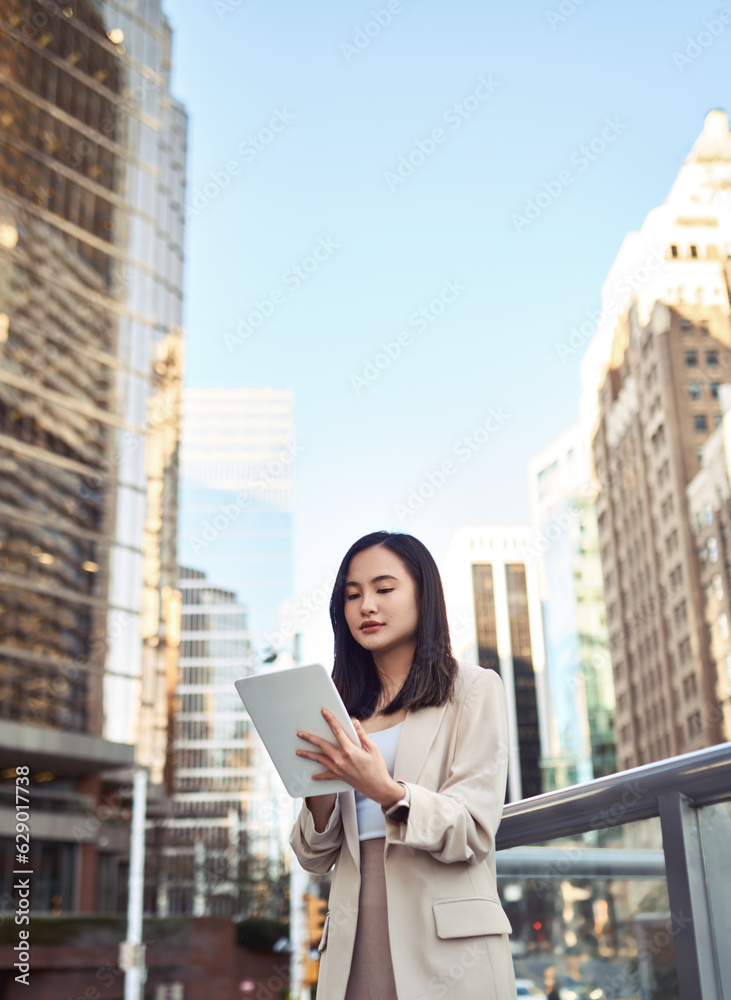 Fototapeta premium Young busy pretty Asian business woman professional office manager executive or global international company employee standing on big city street outside using digital tablet fintech device, vertical.