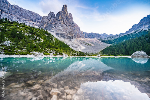 Fototapeta Naklejka Na Ścianę i Meble -  Beautiful reflections on turquoise Sorapis lake and with dito di dio in the background in the evening. Lake Sorapis, Dolomites, Belluno, Italy, Europe.