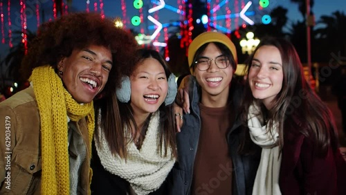 Group of multiethnic friends having fun in a city street during a winter night illuminated at Christmas