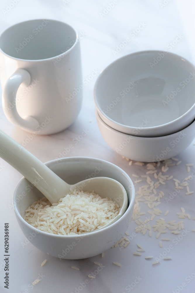 High key white rice in bowl with cup and spoon. High key white rice in bowl with cup and spoon.