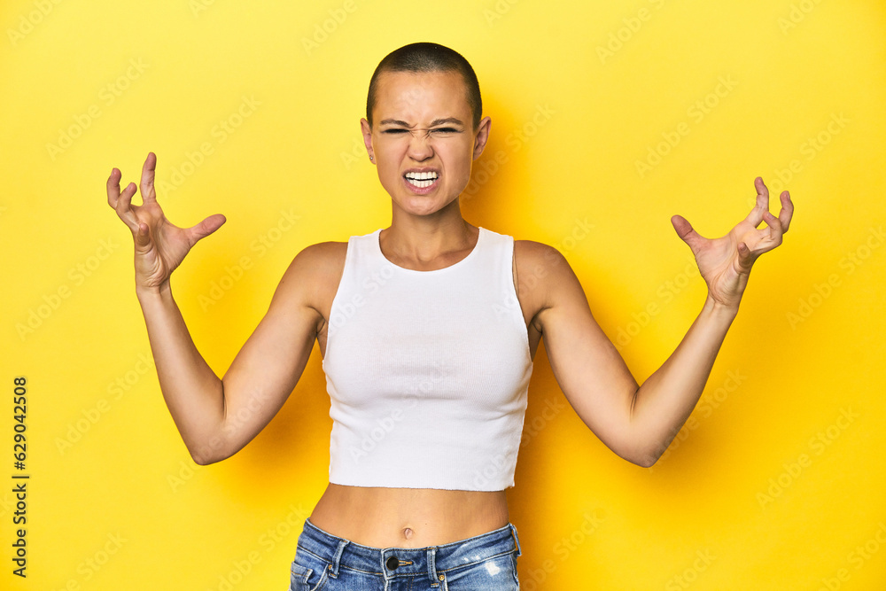 Shaved head woman in white tank top, yellow backdrop screaming with rage. Shaved head woman in white tank top, yellow backdrop screaming with rage.