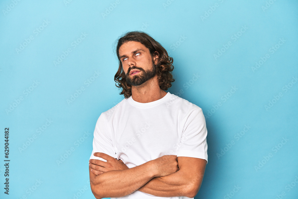 Bearded man in a white shirt, blue backdrop tired of a repetitive task. Bearded man in a white shirt, blue backdrop tired of a repetitive task.
