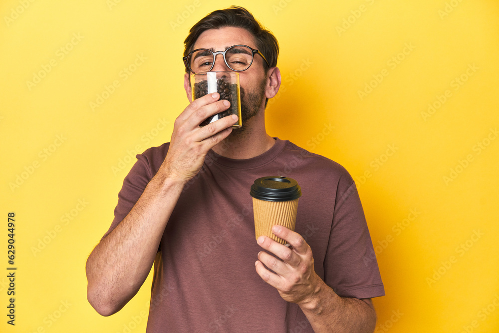 Man letting gourmet coffee beans fall from his hand on yellow studio background. Man letting gourmet coffee beans fall from his hand on yellow studio background.