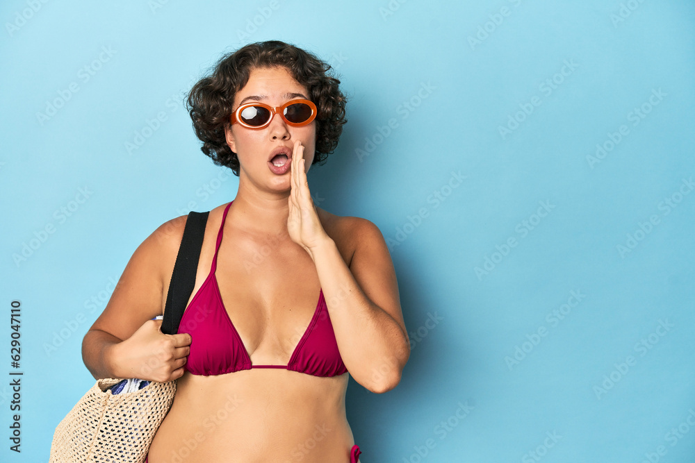 Young woman in bikini with beach bag is saying a secret hot braking news and looking aside