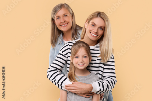 Three generations. Happy grandmother, her daughter and granddaughter on beige background