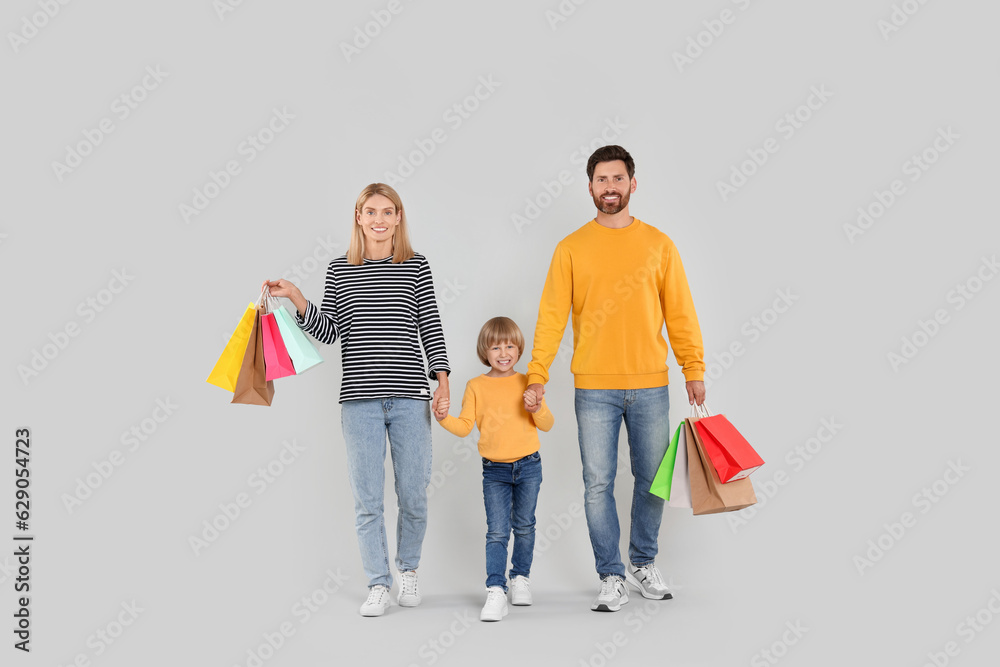 Family shopping. Happy parents and son with many colorful bags on light grey background Family shopping. Happy parents and son with many colorful bags on light grey background