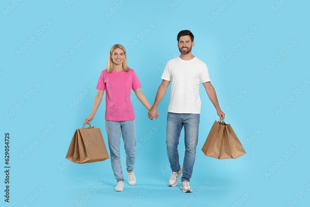 Family shopping. Happy couple with many paper bags on light blue background Family shopping. Happy couple with many paper bags on light blue background
