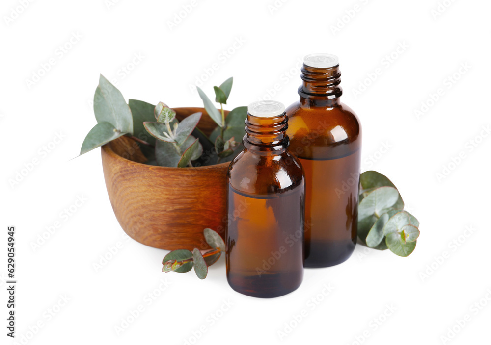 Bottles of eucalyptus essential oil and bowl with plant branches on white background Bottles of eucalyptus essential oil and bowl with plant branches on white background