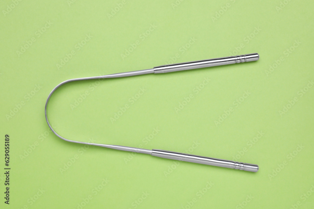 Metal tongue cleaner on light green background, top view Metal tongue cleaner on light green background, top view