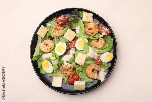 Delicious Caesar salad with shrimps on beige table, top view