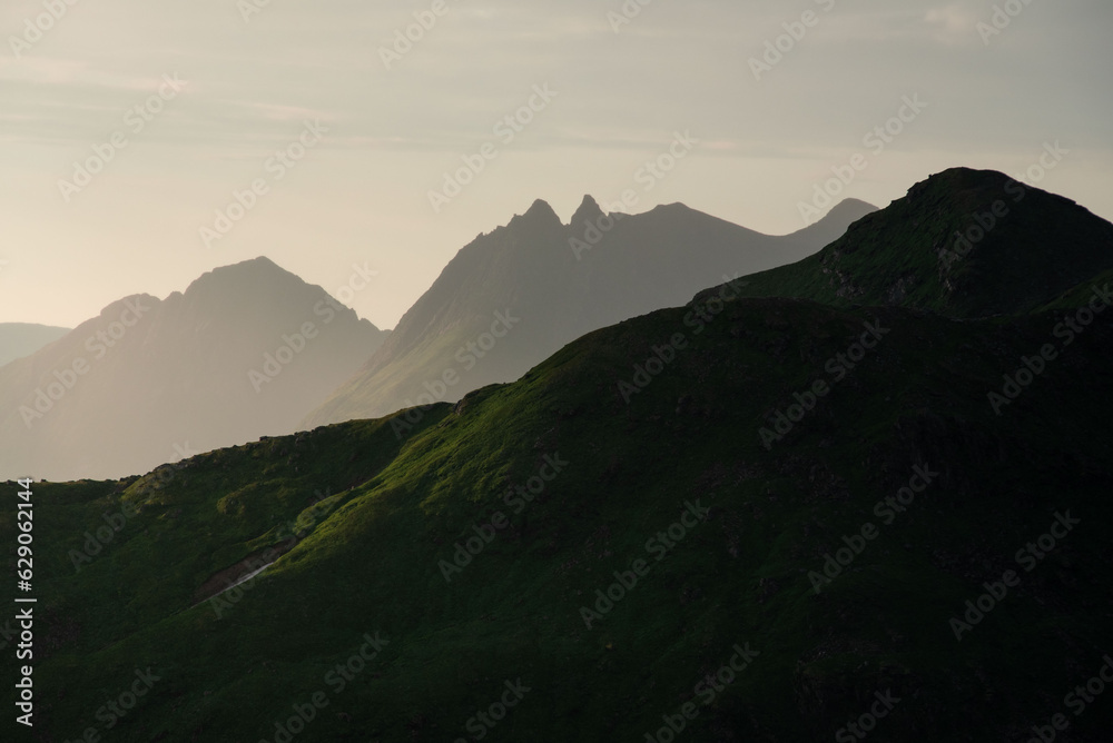 Abstract norwegian landscape at sunset, Smaltinden, Luröy, Helgeland, Nordnorge. Post summer storm dusk with mountain silhouettes. Green details in dark mountains scandinavia. Topptur sommarnatt. 