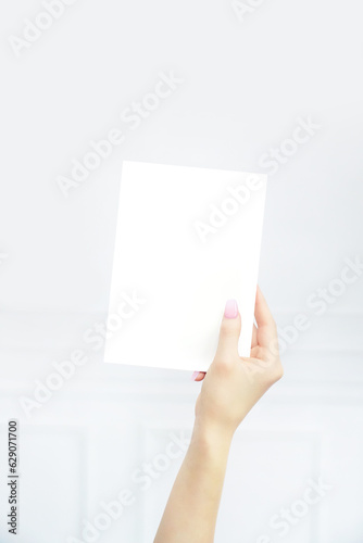 Woman's hand holding blank 5x7 invitation card, white background photo