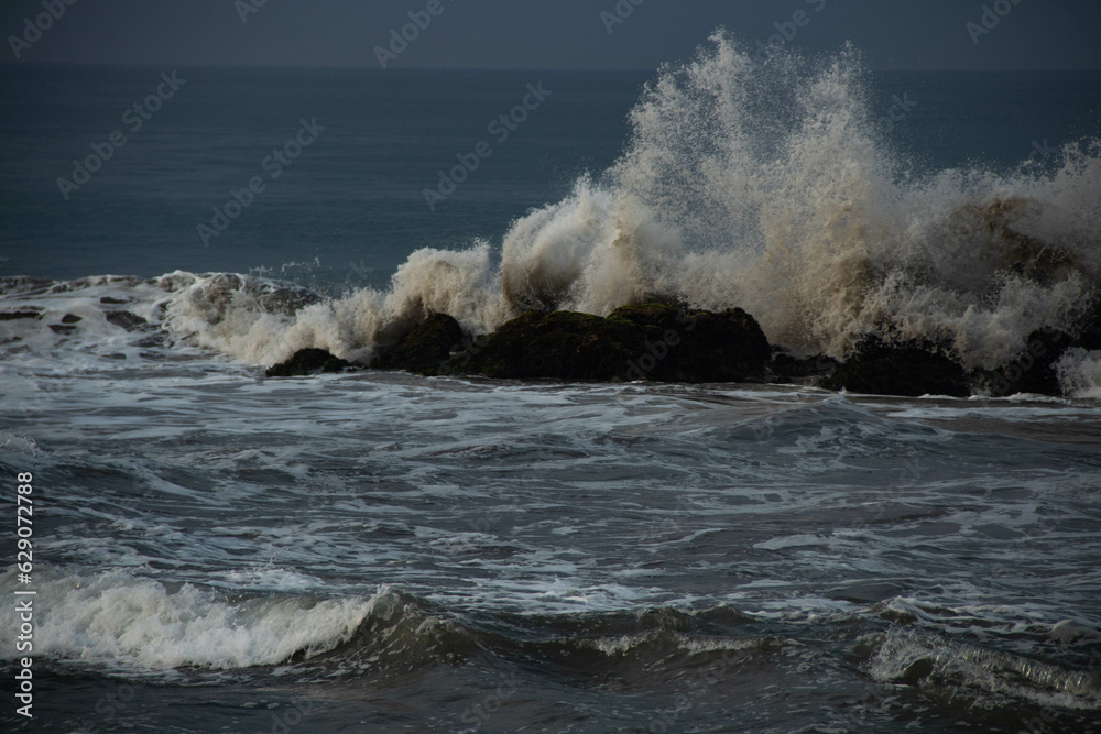 Fototapeta premium Waves crashing against rocks on the seashore