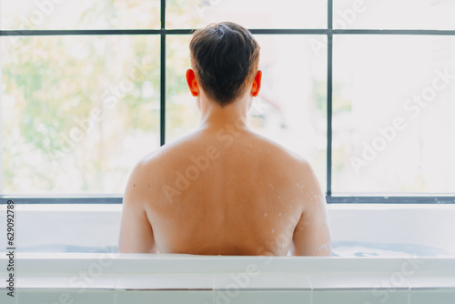 Back of asian man showering in the bathtub in the bathroom.