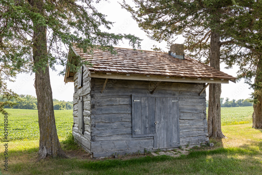 Rural landscape view of a 19th century log cabin on the prairie in midwestern United States