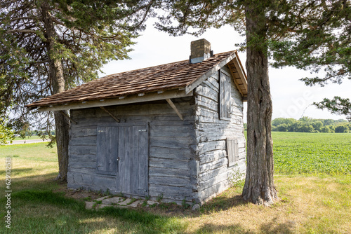 Rural landscape view of a 19th century log cabin on the prairie in midwestern United States © Cynthia