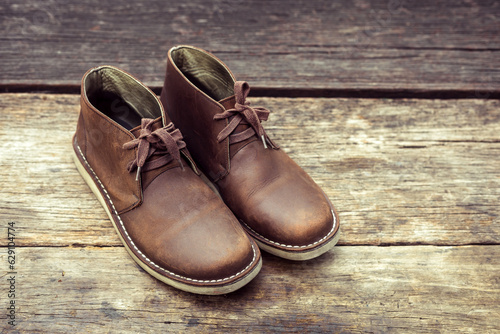 Brown stylish boots on wood background,  retro color © PRASERT