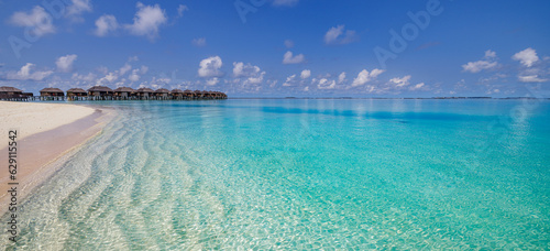 Amazing Maldives panorama. Luxury resort villas seascape. Closeup calm waves white sand blue sky clouds. Beautiful summer landscape. Amazing beach coast for travel vacation. Tropical paradise island
