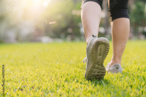 jogger woman. close up person training sport runner young female shoe on grasses in public park. fitness leg and foot exercise athlete. marathon in nature. active healthy lifestyle workout concept.