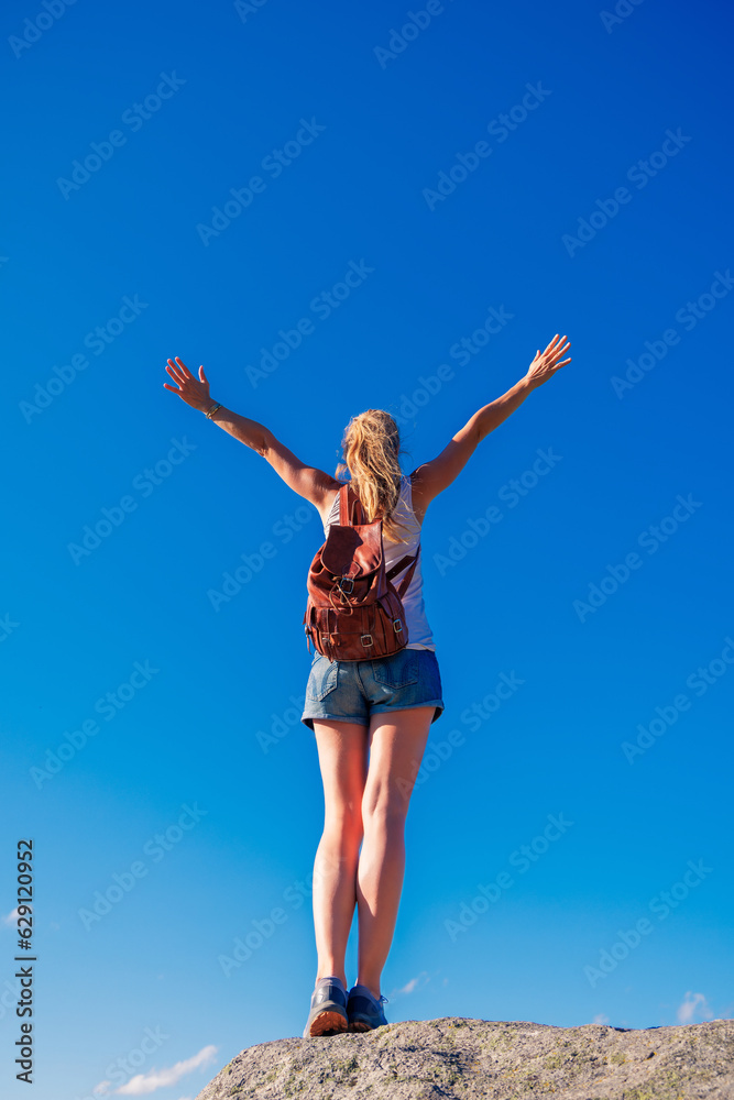 Woman standing on cliff with open arms against blue sky- freedom, achievement, Woman standing on cliff with open arms against blue sky- freedom, achievement,