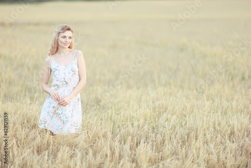 romantic girl posing in a summer field dress