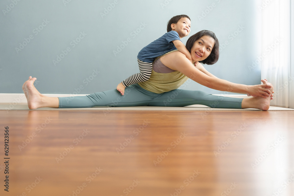 Asian Mother playing with her son during fitness at home. Chinese Woman and adorable boy enjoying yoga together. Wellness, Healthcare