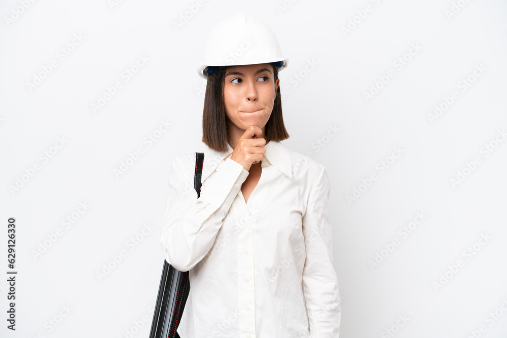 Young architect woman with helmet and holding blueprints isolated on white background having doubts and thinking Young architect woman with helmet and holding blueprints isolated on white background having doubts and thinking