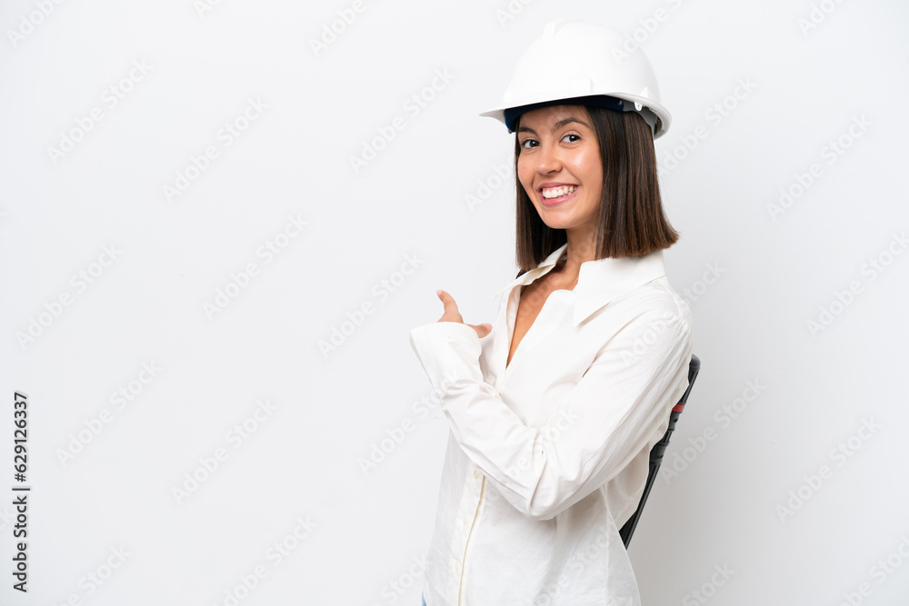 Young architect woman with helmet and holding blueprints isolated on white background pointing back Young architect woman with helmet and holding blueprints isolated on white background pointing back