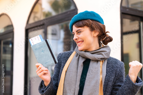 Brunette woman holding a passport at outdoors celebrating a victory © luismolinero