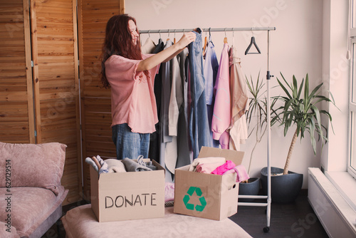 Smiling young woman putting clothing into donation box photo