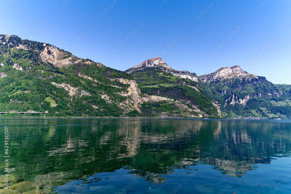 Scenic view of Lake Lucerne with Swiss Alps and mountain panorama seen from lakeshore of village Flüelen on a sunny spring day. Photo taken May 22nd, 2023, Flüelen, Switzerland.