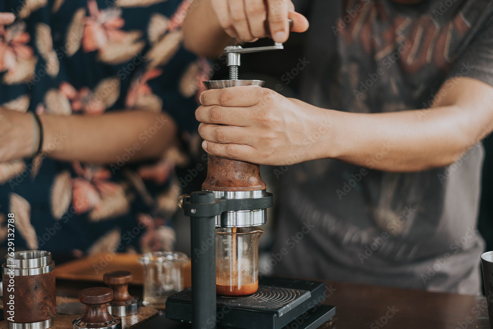 Professional barista making fresh coffee from ARAM espresso machine. Close up of hands barista brewing dirty coffee by handmade coffee machine in counter coffee shop.