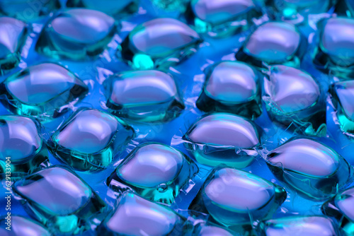 Background lot of capsules for washing green on blue background.