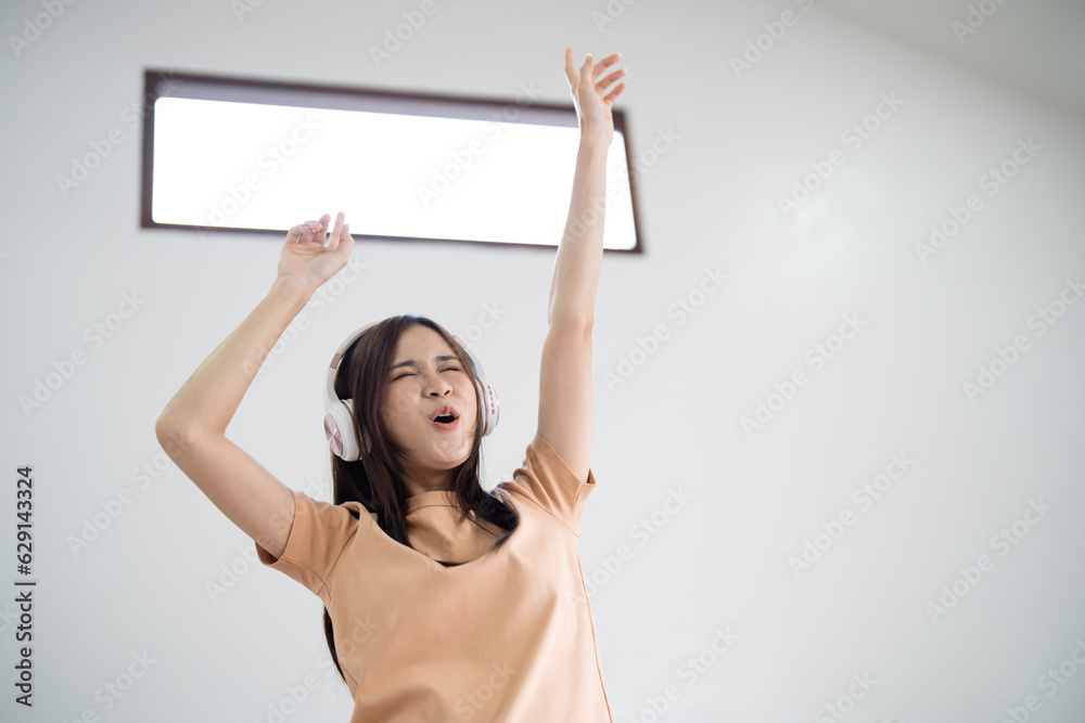 Happy Young Asian woman wearing headphone have fun and dancing listening to music relax in living room. beautiful joyful woman dancing in house Happy Young Asian woman wearing headphone have fun and dancing listening to music relax in living room. beautiful joyful woman dancing in house