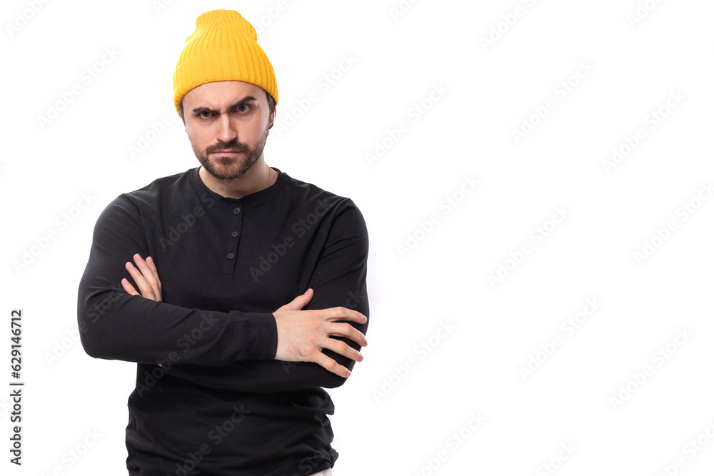 brutal handsome young 30 year old guy dressed in a black jacket and a yellow hat on a white background with copy space