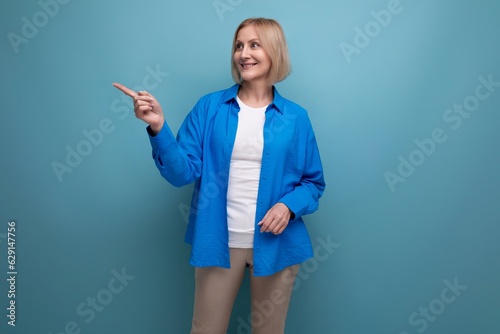 50s woman in blue shirt with idea on blue background with copy space