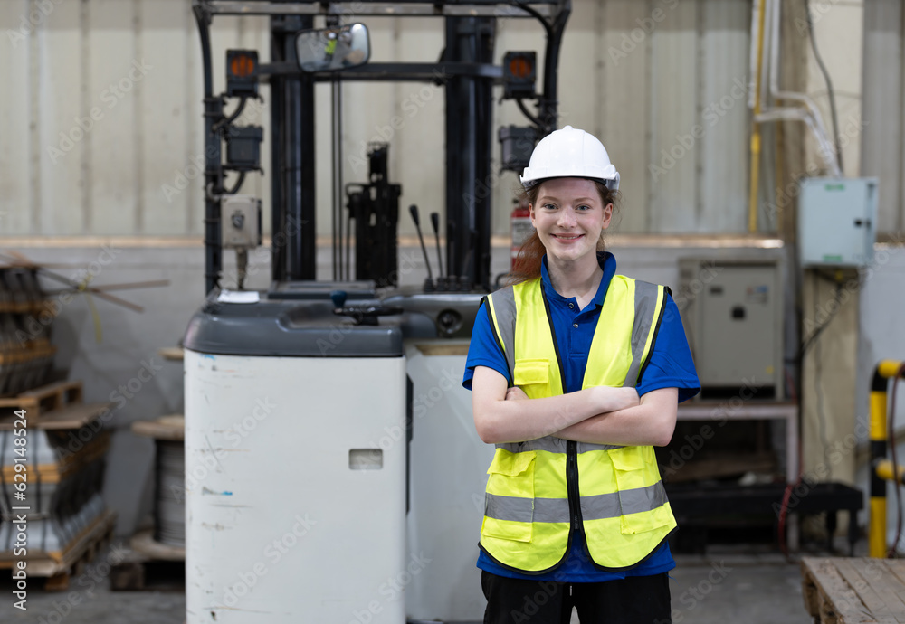 Portrait of female warehouse worker or woman driver forklift smile and standing with arms crossed in warehouse. Logistics, Distribution Center concept Portrait of female warehouse worker or woman driver forklift smile and standing with arms crossed in warehouse. Logistics, Distribution Center concept