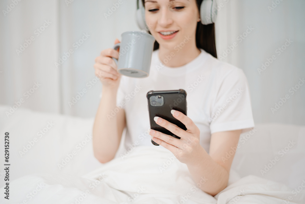 Beautiful woman has woken up on a white bed and holding coffee in the morning at home in morning Beautiful woman has woken up on a white bed and holding coffee in the morning at home in morning