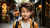 Happy Asian boy smiling in the city. Closeup Portrait of a joyful Japanese kid standing on a city street. Cheerful pre-teen Asian child outdoors looking at the camera, closeup. .
