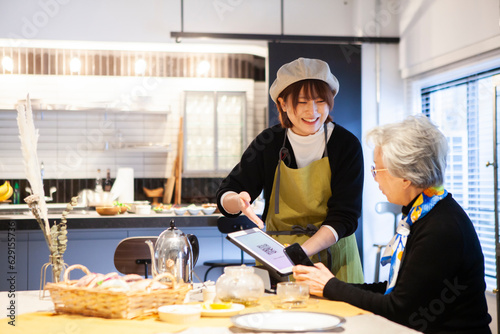 QRコードでのメニュー表示をお客のシニア女性に案内するカフェの店員