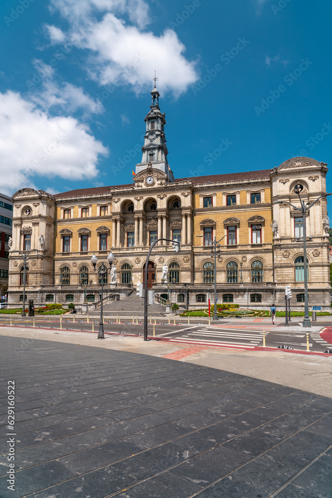 Bilbao, SPAIN - July 19 2022: Beautiful City Hall building of the Bilbao city, built in Baroque style. In front of the building is the river Nervion. People passing. Travel destination in Spain