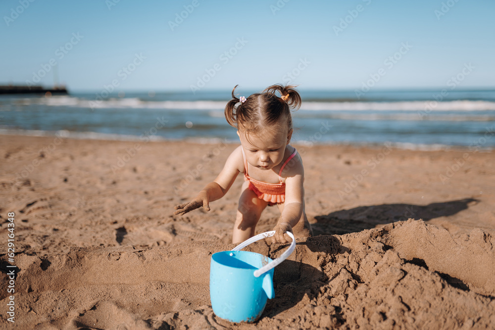 little child sea, girl in swimsuit joyful plays on the beach little child sea, girl in swimsuit joyful plays on the beach